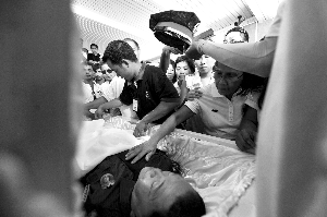 28日，兇手門多薩身著警服躺在棺木里。