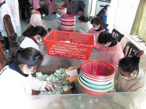 點(diǎn)鈔員們在低頭緊張地工作，她們每人每天都需要點(diǎn)鈔25箱1萬元以上。 陳暄 攝