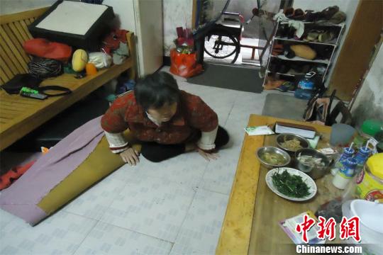 17日下午，56歲小兒麻痹癥患者張紅英爬在地板上找東西。 蘇路程 攝
