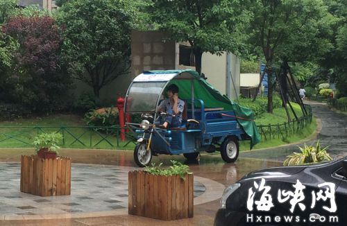 這名快遞哥騎行在小區(qū)通道內(nèi)，一邊接打手機，一邊還把腳架在車前欄桿上